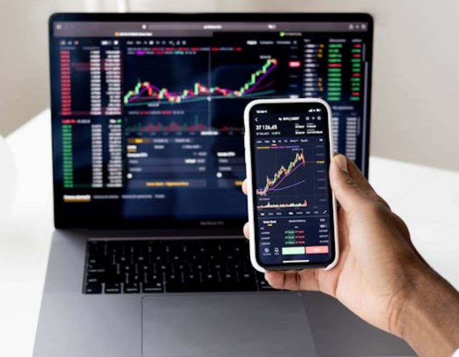 a person analysing a graph on a laptop while holding a phone