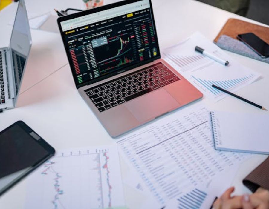 a gray laptop on a table with papers surrounding it