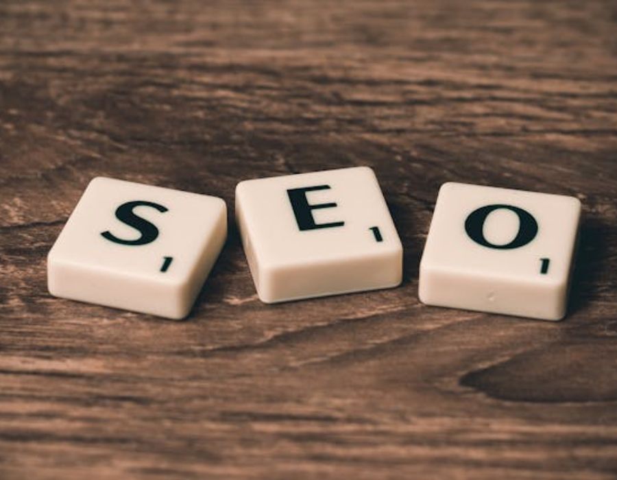 Three White-and-black Scrabble Tiles on Brown Wooden Surface written on SEO