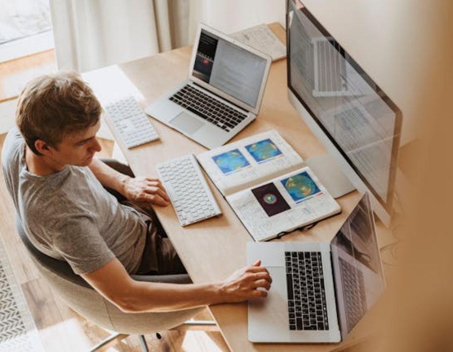 a person different computers at a time with an open book on the table
