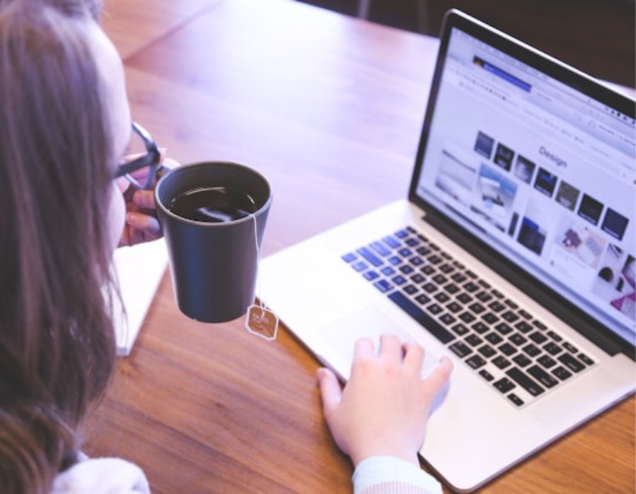 a woman analysing some content on the laptop as she takes tea