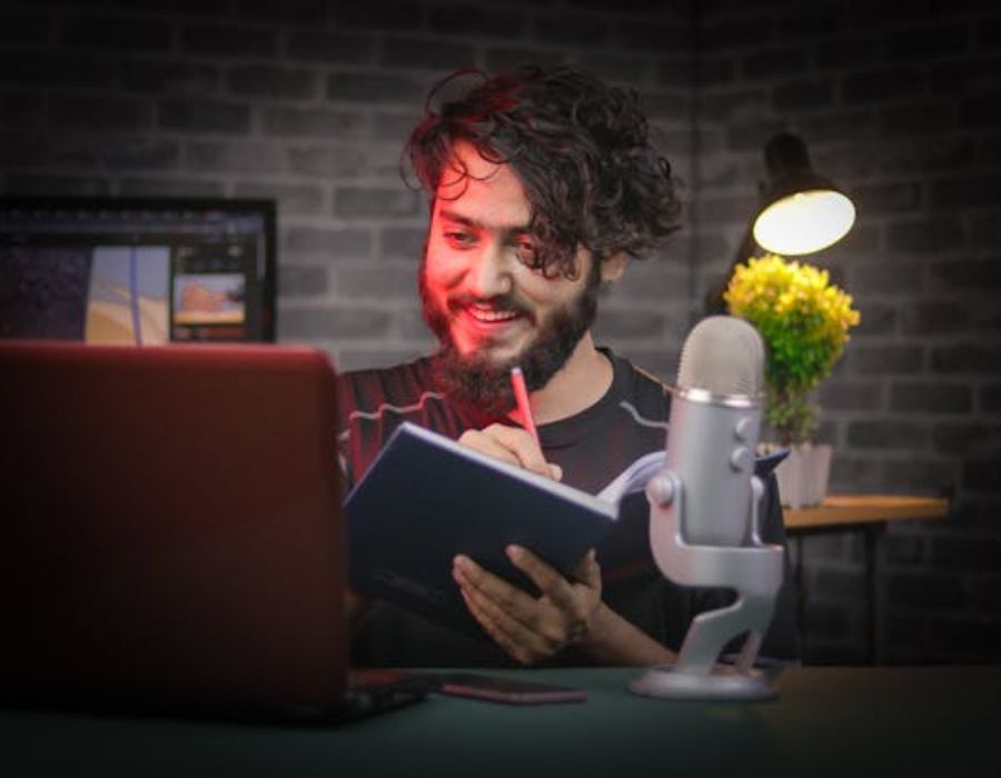A Man Sitting at a Table with Laptop and Microphone