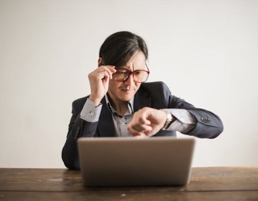 a man taking a look at his watch while using a laptop