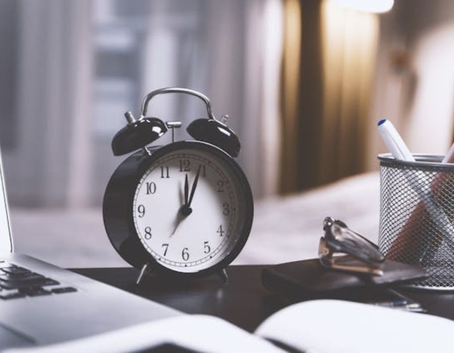 a clock on a table with stationeries on the side